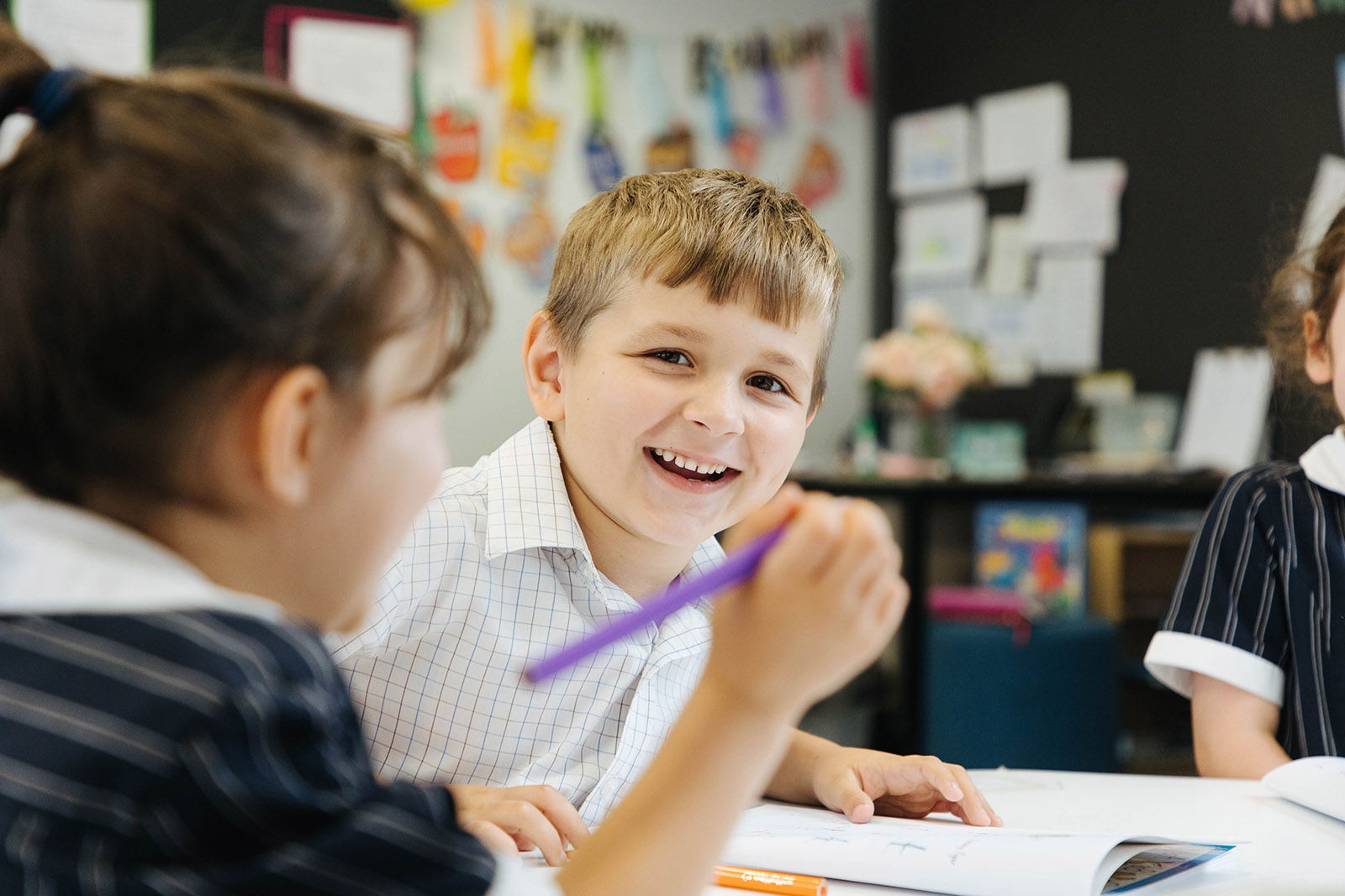Smiling kindergarten student using workbook in Australian Christian College Burnie classroom