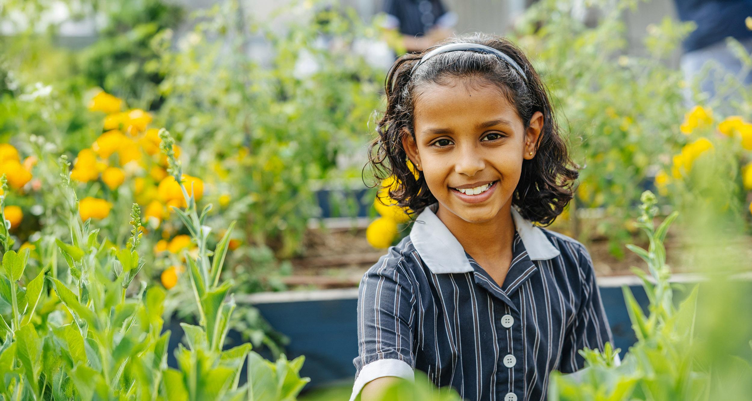 Primary student smiling in the school garden at ACC Moreton.