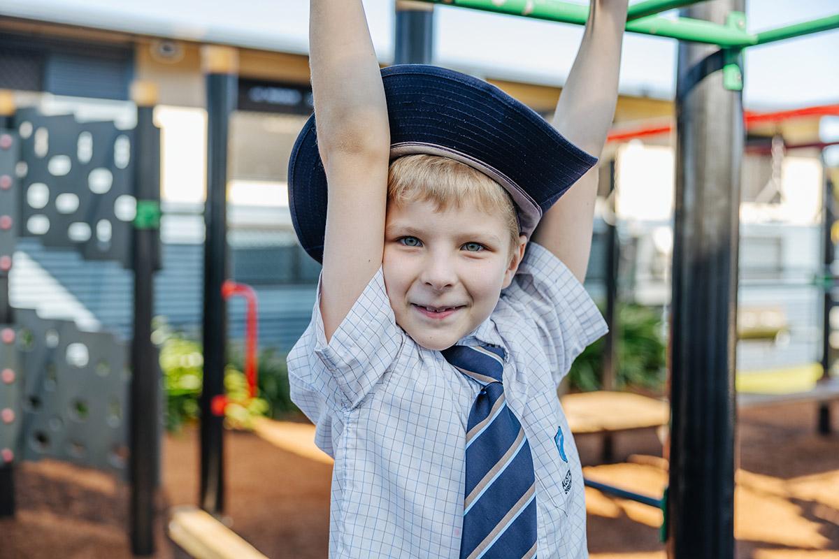 Student smiling on playground equipment during a campus tour at ACC Moreton.