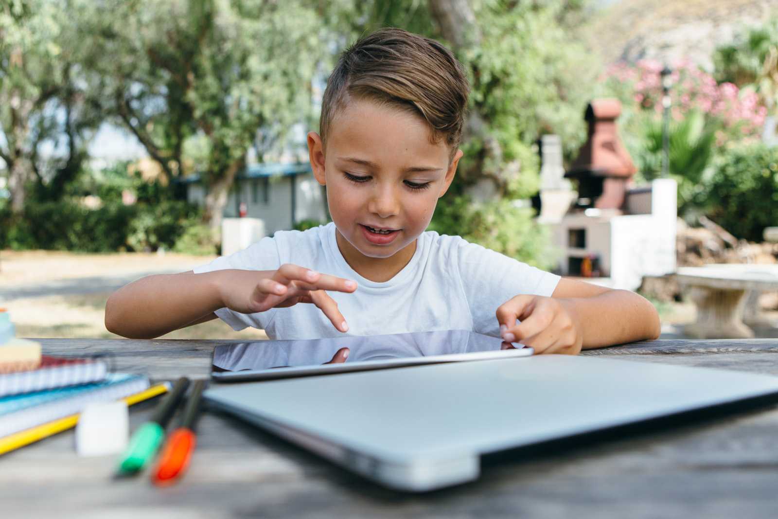 boy sitting outside completing lesson on a tablet