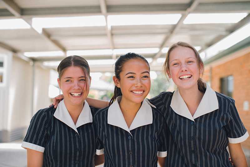 Singleton high school students with arms around each other laughing