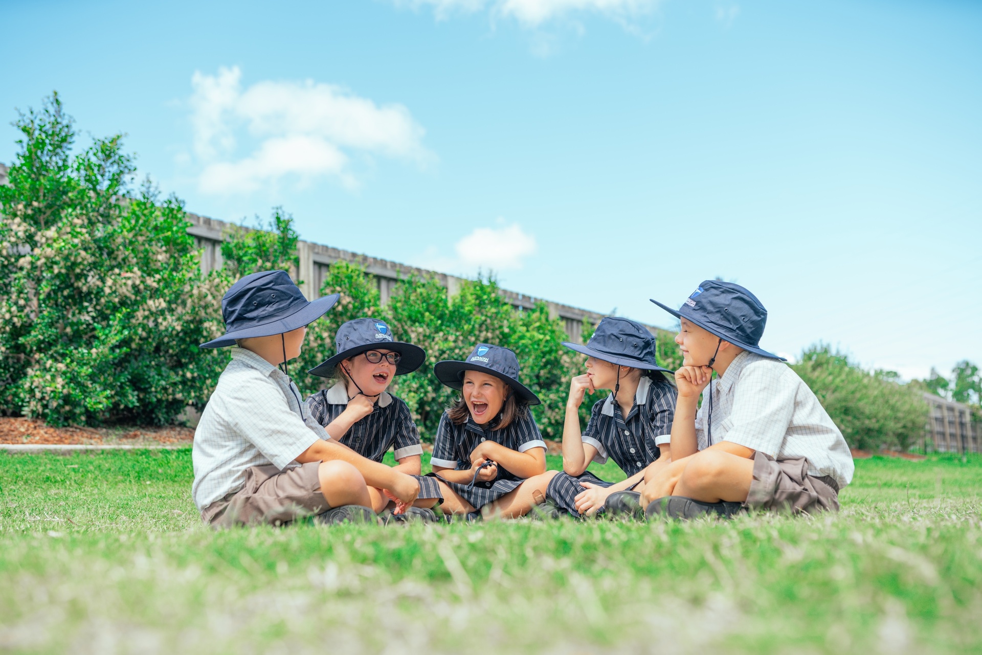 Students sitting on the oval wearing broad-brim hats at ACC Benalla school campus