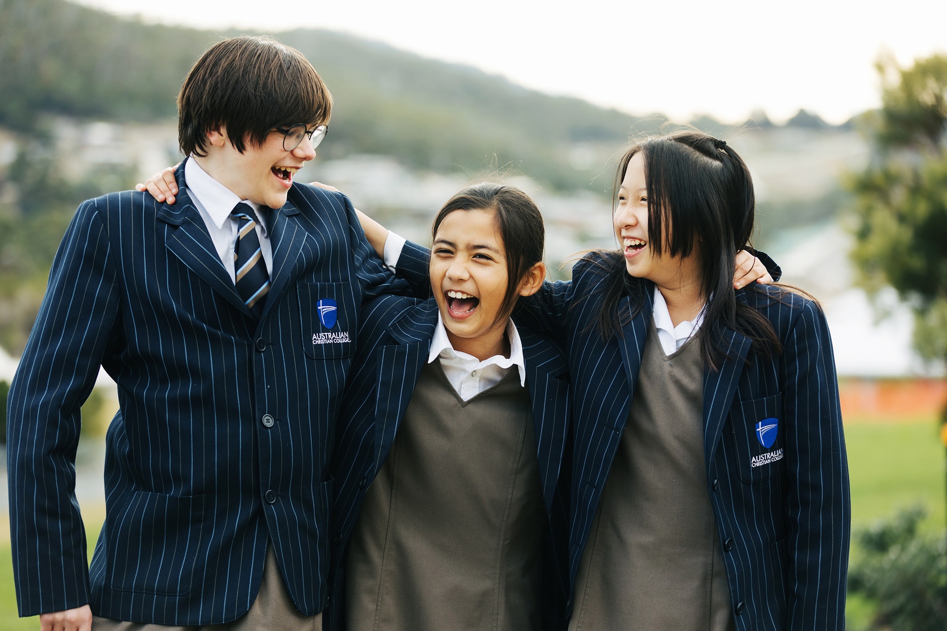 ACC Benalla students wearing formal winter uniform laughing together with arms around one another