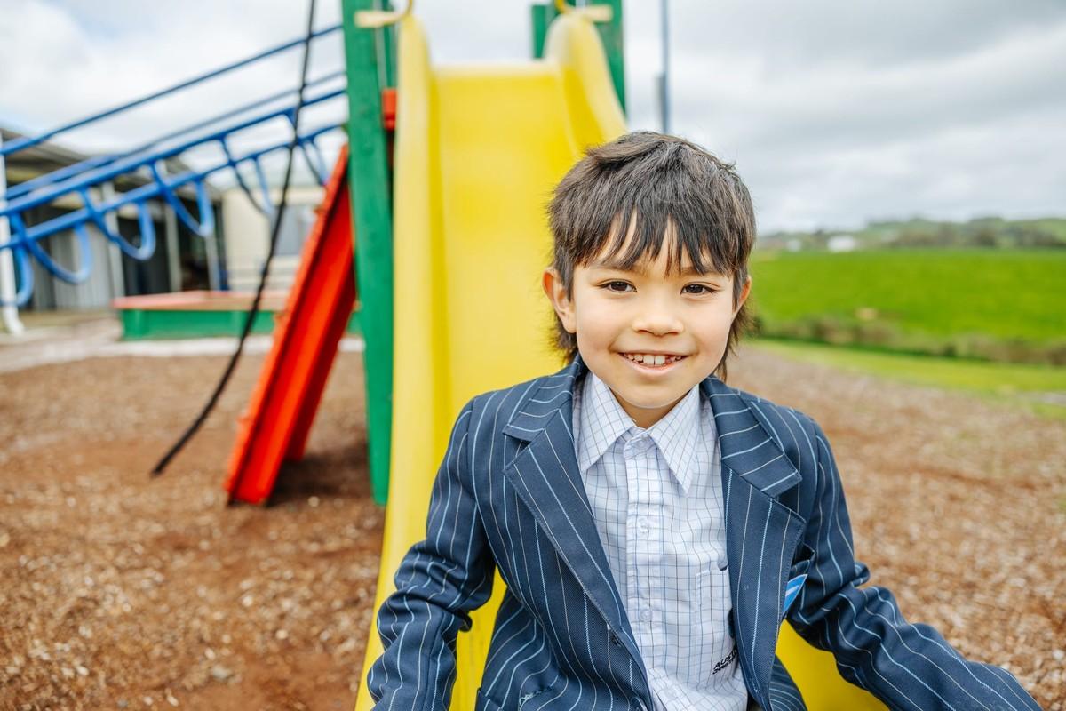 Young primary student smiling at the playground slide at ACC Burnie