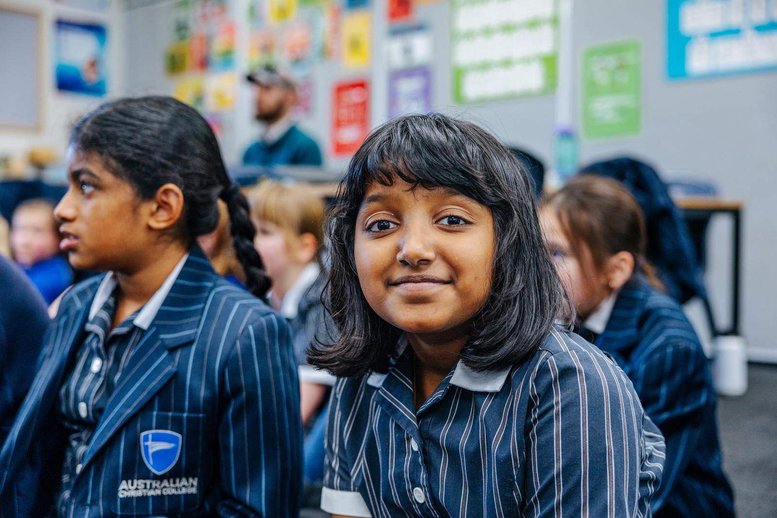 Primary student smiling in an ACC Hobart classroom with classmates