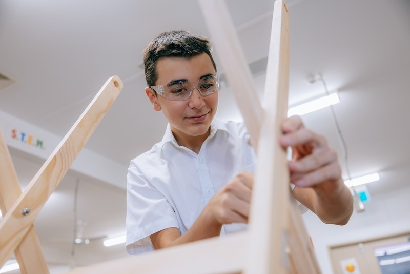 Singleton High School boy woodworking wearing safety glasses