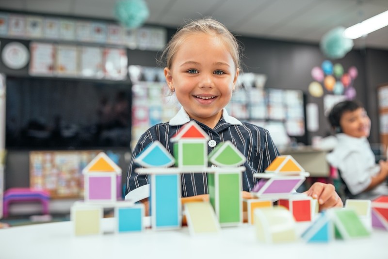 Kindergarten girl actively learning playing with blocks in classroom