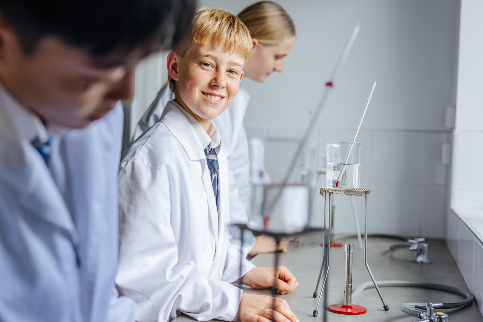 Secondary students in lab coats conducting a science experiment at ACC Southlands