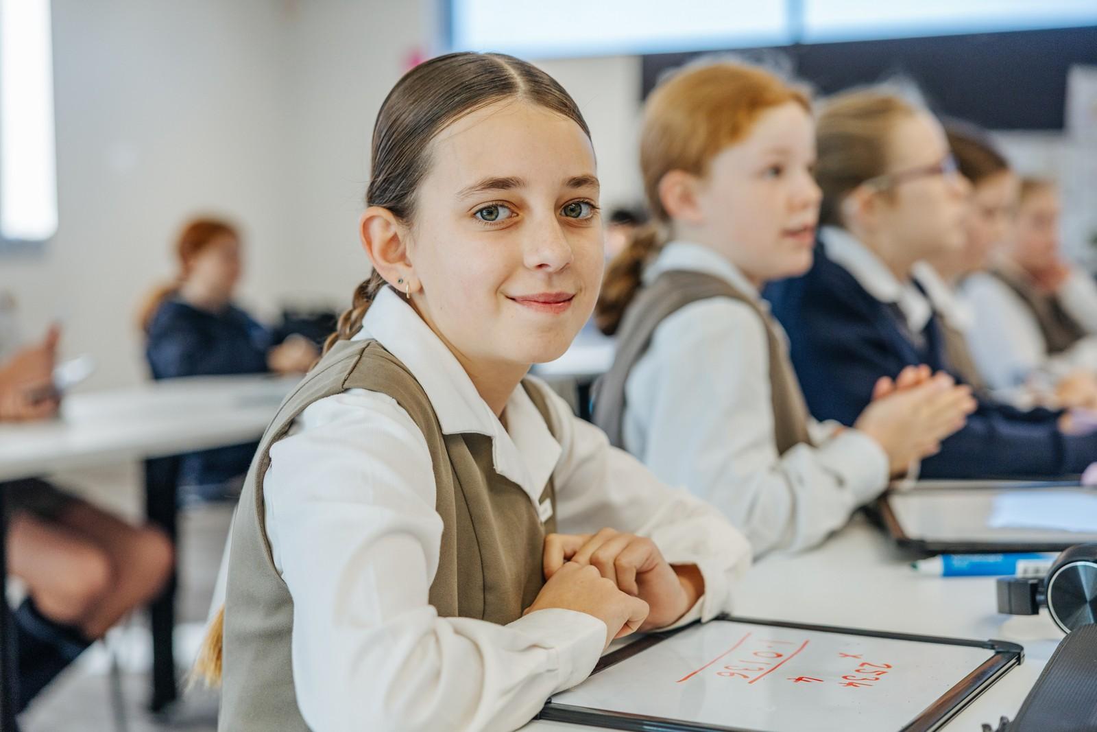 Upper primary girl working at her desk in a classroom at Albany school