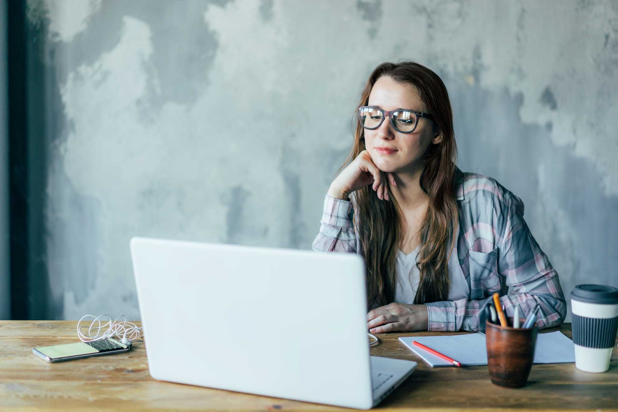 Girl with curly hair wearing jumper and headphones completing distance education online